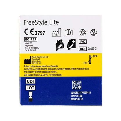A square product box for an Abbott FreeStyle Lite blood glucose meter, featuring a white top half with black text and icons, a bright yellow middle band with patent text, and a blue bottom band with UDI/LOT details and a QR code.